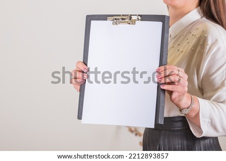 Woman holding clipboard with a blank sheet of paper. Blank paper poster in female hands. Blank template for graphic designers portfolios. To do plans in business, blogging, educations
