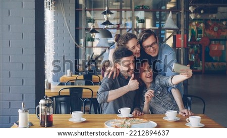 Happy best friends are taking selfie laughing posing making funny faces and gestures hugging at lunch in cafe. Social media, friendship, millennials and free time concept.