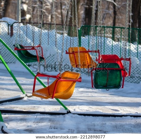 Children's swing in the snow in the park. Winter