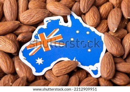 Small paper map and flag of Australia on almond nuts. Concept of growing almond in Australia, origin of almond