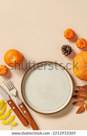 Autumn Halloween or Thanksgiving day table setting. Autumn background with an empty plate, cutlery, pumpkins. Thanksgiving background mock up. View from above. Copy space.