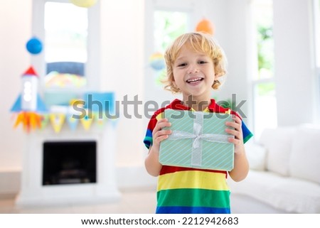 Space theme kids birthday party. Boy with present. Children celebration with astronaut, rocket, planets of solar system decoration. Family festive event. Royalty-Free Stock Photo #2212942683