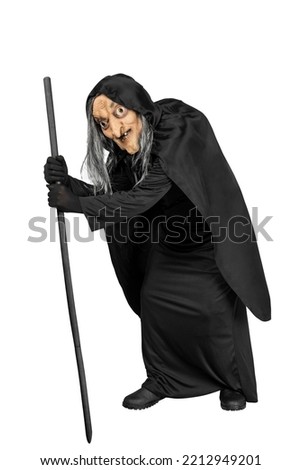 Old witch in a cloak standing with a stick isolated over white background