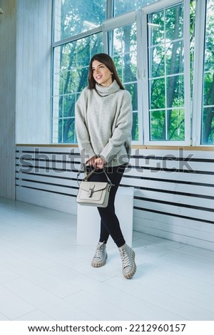 Photo of a young woman in white boots and casual clothes. New collection of women's winter shoes made of genuine leather.