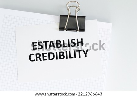 ESTABLISH CREDIBILITY text on a card clip to a notepad on the table