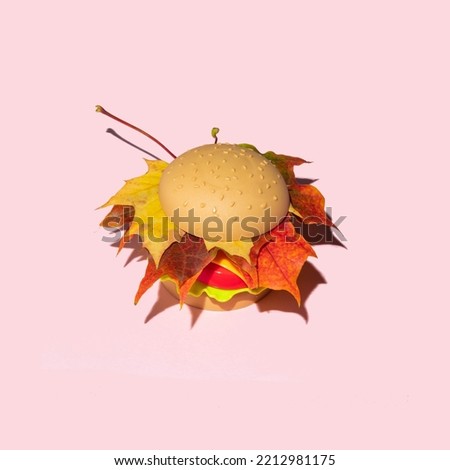 Pastel autumn concept. Sandwich with red leaves on light pink background. Minimalistic fall composition.