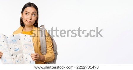 Image of young asian girl tourist, traveller with map and backpack posing against white studio background