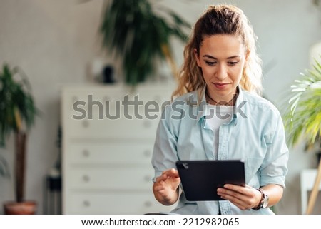 Photo of an adult girl, holding and using a digital tablet.