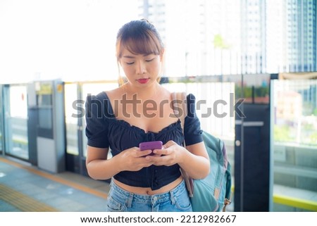 Beautiful asian woman use smartphone travel in city train with backpack