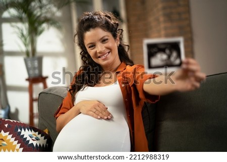 Pregnant woman with ultrasound photo. Beautiful pregnant woman enjoy at home