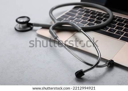 Laptop with stethoscope on white table, closeup. Space for text