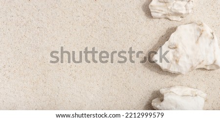 Natural cosmetic background for product presentation. White rocks on the sand. Top view.