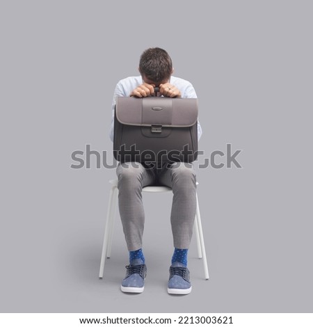 Bored man sitting on a chair and waiting for a meeting or a job interview, he is nervous and scared