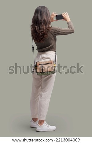 Young beautiful woman taking pictures with her smartphone, back view Royalty-Free Stock Photo #2213004009