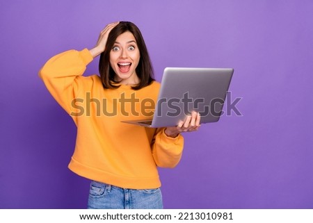 Portrait photo of youngster pretty woman wear yellow sweater touch head unexpected surprised reaction hold computer app isolated on purple color background