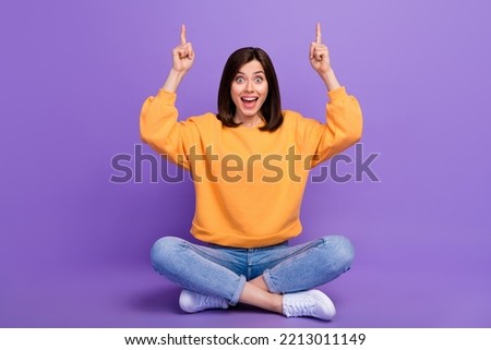 Full body length photo of young adorable excited girl fingers pointing empty space sitting celebrate halloween event isolated on bright purple color background