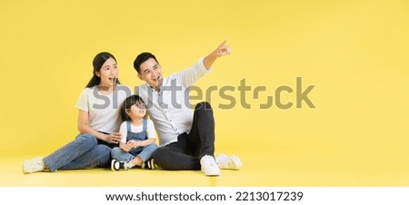 Image of Asian family sitting together happy and isolated on yellow background
