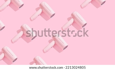 Trendy pattern made of hair dryer on sunny pink background with diagonal copy space. Creative hairdressers wallpaper. Royalty-Free Stock Photo #2213024805