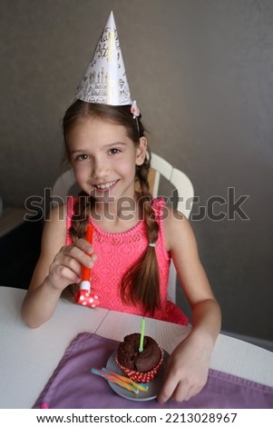birthday girl in a festive cap blows on candles on her birthday