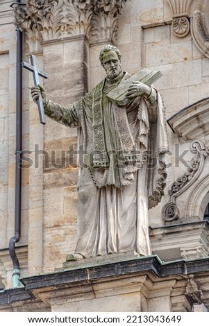 Old roof statute of priest or monk holding a big cross at Dome base of the Cathedral of Holy Trinity, historical center of Dresden, Germany