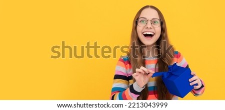 happy teen girl in eyeglasses opening gift box for birthday. Teenager girl with birthday gift, horizontal poster.