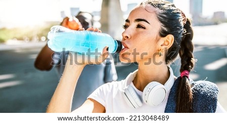 Fitness female athlete drinking energy drink outdoor - Fit people resting taking a break after workout - Healthy lifestyle and sport concept