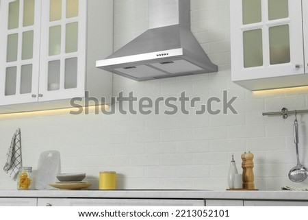 Elegant kitchen interior with modern range hood over cooktop and stylish furniture Royalty-Free Stock Photo #2213052101