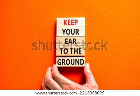 Keep your ear to the ground symbol. Concept words Keep your ear on the ground on wooden blocks. Businessman hand. Beautiful orange background. Business keep your ear on the ground concept. Copy space.