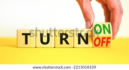 Turn on or off symbol. Concept words Turn off and Turn on on wooden cubes. Beautiful yellow table white background. Businessman hand. Business Turn on or off concept. Copy space.