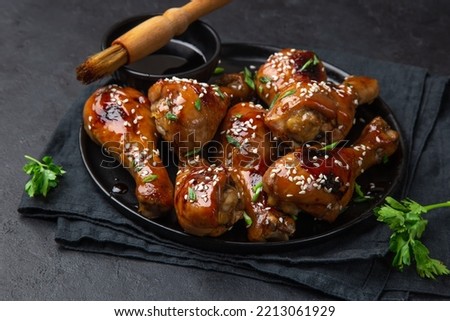 glazed teriyaki chicken legs on black plate, selective focus