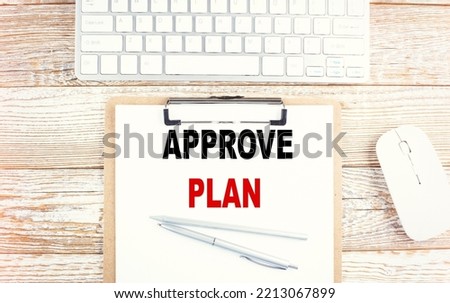 APPROVE PLAN text on clipboard with keyboard on wooden background
