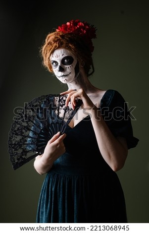 Elegant scary halloween costume. Mexican Day of the Dead Tradition. Skull with flowers makeup for a party. Party ideas. Mysterious portrait of a woman with a painted face. scary face. dark background