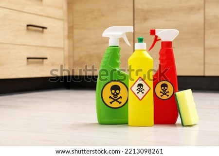 Bottles of toxic household chemicals with warning signs and scouring sponge on floor indoors, space for text Royalty-Free Stock Photo #2213098261