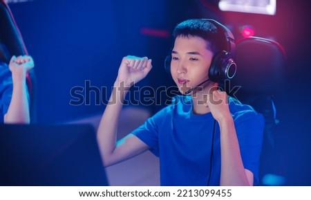 Winner Young asian man pro gamer streamer playing in online video game, neon color soft focus. Concept banner cyber esport Korean.