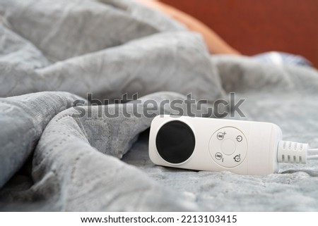 controller of an electric blanket with a human sleeping at the background at horizontal composition Royalty-Free Stock Photo #2213103415