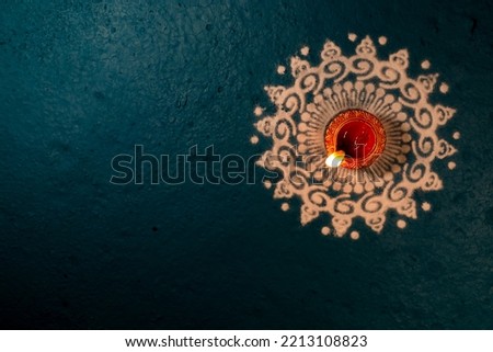 India, 4 October, 2022 : Happy Diwali Festival of Lights teal color background with red and golden color traditional clay oil lamp Diya lit on white color Rangoli design during Deepavali celebration. Royalty-Free Stock Photo #2213108823