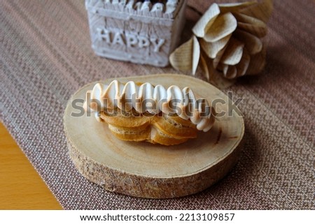 Eclair topped with toasted swirl of meringue and filled with lemon in landscape dimension