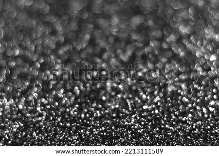 Gray black sparkling glitter bokeh background, abstract defocused texture. Holiday lights. Snowy shiny sparkle stars for celebrate
