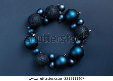 Circle frame of blue matte and glitter Christmas balls on dark blue background with copy space