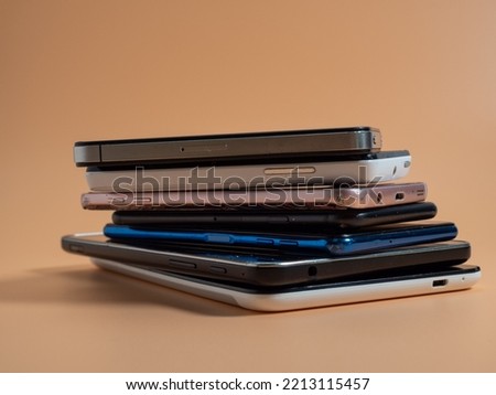 Old broken smartphones. Smartphones on an orange background. Close-up. Royalty-Free Stock Photo #2213115457