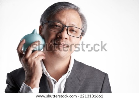 senior chinese man with formal wear eyeglasses holding piggy bank against white background