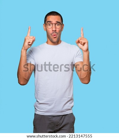 Amazed young man pointing up with his finger