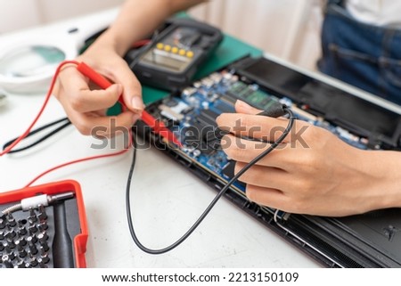 Asian woman using a power meter to check laptop board to repair or replace. Selective focus her hand.