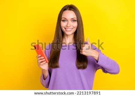 Closeup photo of young adorable pretty businesswoman influencer hold phone showing thumb up like new app for finance isolated on yellow color background