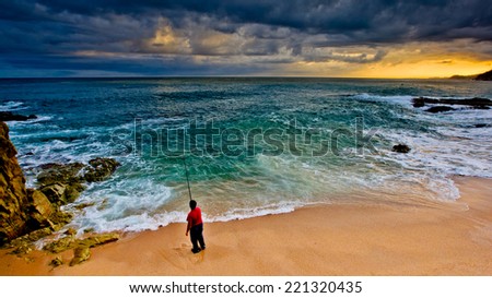 Fisherman on the Beach as a storm approaches at sunset