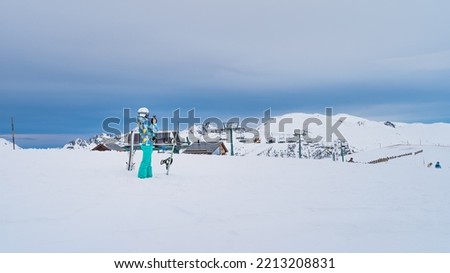 Woman skier taking a picture of a ski lift on the top of snowy Pyrenees Mountains. Skis planted in deep snow. El Tarter, Grandvalira, Andorra