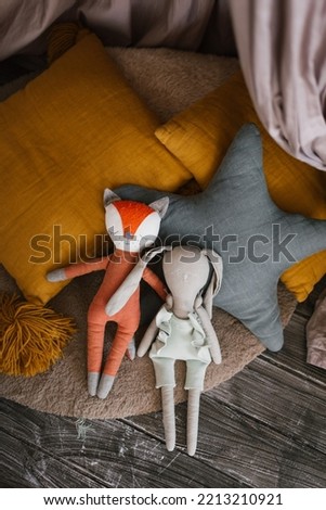 Homemade stuffed toys lie next to brightly colored pillows