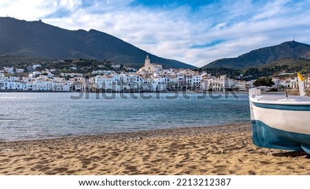 View of the city of Cadaques, Spain, with a fishing boat in the foreground. Taken in winter during a party sunny winter afternoon with some unrecognizable people in the far background