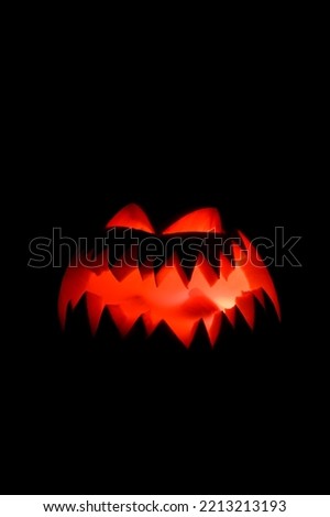 view on burning halloween pumpkin with illuminated carved mouth and eyes in dark. Jack-o-lantern decoration