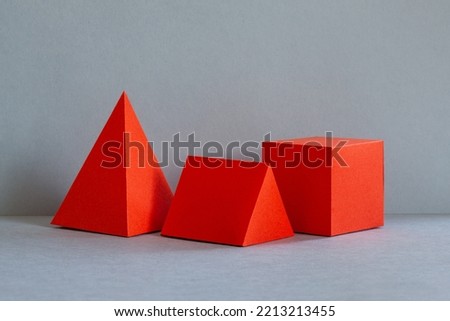 Red abstract geometrical figures on gray background. bright three-dimensional pyramid rectangular cube objects. Platonic solids figures, simplicity concept photography